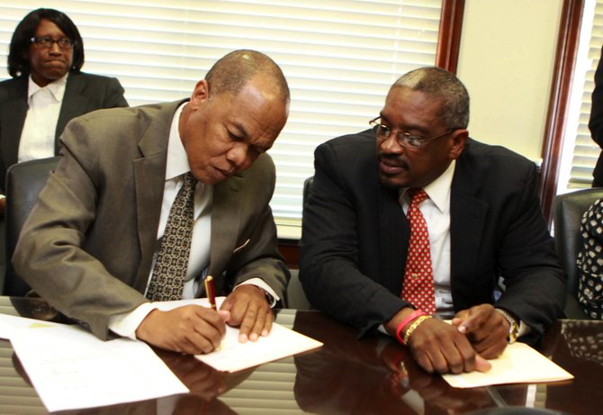 Herbert Brown, managing director of the PHA and Dr Hubert Minnis, Minister of Health, sign the deal to acquire the Island Palm Hotel.