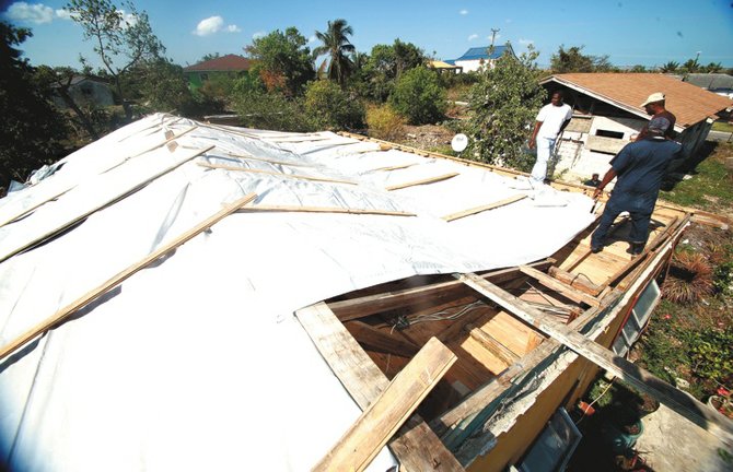 Bahamas Defence Force members help to repair a home whose roof was ripped off by the storm.