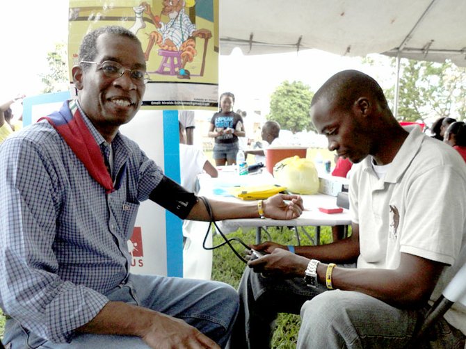 Haitian Ambassador Antonio Rodrigue (left) has his blood pressure checked on site by a Ministry of Health nurse.