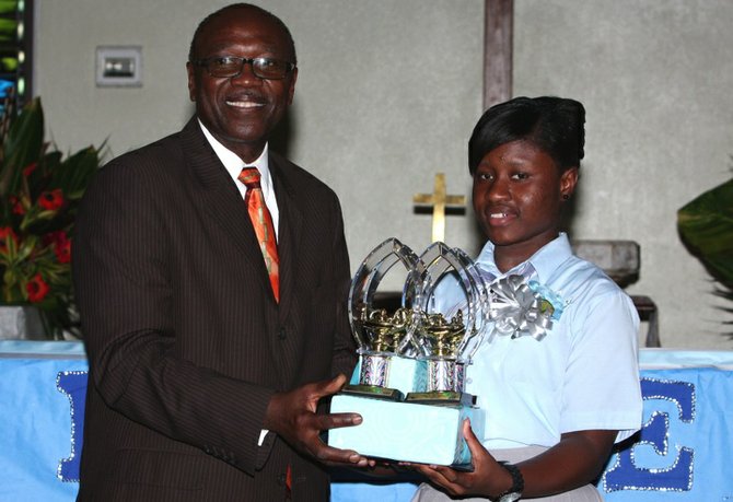 Toni Johnson accepts awards for most improved student in social studies and straw-craft and most outstanding student in math from Superintendent of the Northwestern District Howard Newbold.