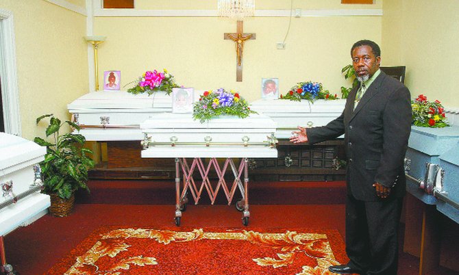 Kemuel Cox, President and CEO of Rock of Ages, stands next to the coffin of one of the drowned victims at the Rock of Ages funeral home on Friday.