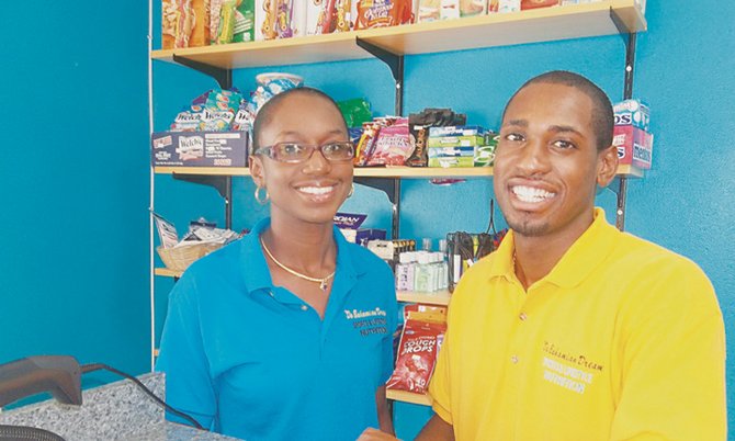 OPEN FOR BUSINESS: Quarter-miler Andretti Bain and his wife Cheryse Rolle-Bain, a local volleyball star, are all smiles inside their newly opened sports and lifestyle nutrition store on Farrington Road and George Street. 
