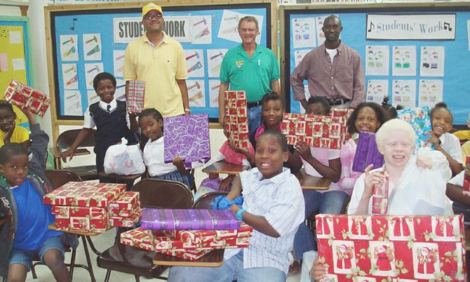 Children at one of the schools happily display their gifts as club members Adrian Hanna, Murray Forde and John Damas look on.