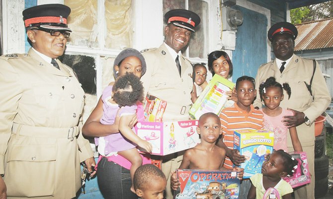 Supt Carolyn Bowe, Supt Stephen Dean and Insp Ricardo Richardson give gifts to children off Fritz Lane and Third Street yesterday afternoon.
