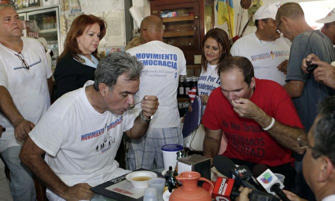 Cuban migrants Ramon Saul Sanchez, center left, president of the Democracy Movement, and Jesus Alexis Gomez break their fast after a news conference in Miami, Monday. (AP)