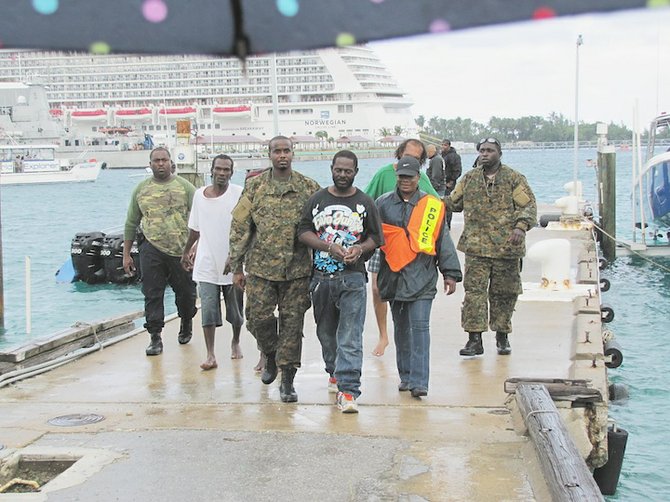 Three men are led away at Nassau Harbour.