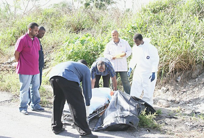 Police remove the partially burned body of a man from a dirt road off Cowpen Road.