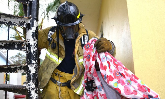 A firefighter leads a fire victim to safety from the blazing home on East Bay Street. 
Photo/Rodney Moncur, Justice of the Peace
