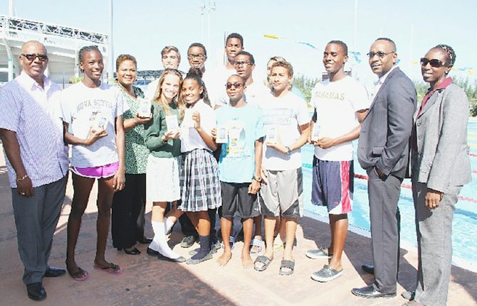 WINNING THE GOLD: Shown are Algernon Cargill (far left), Carol Barnett (3rd from left), Jerome Sawyer and Zelda Allen (far right) with some members of the CARIFTA swim team yesterday.
        