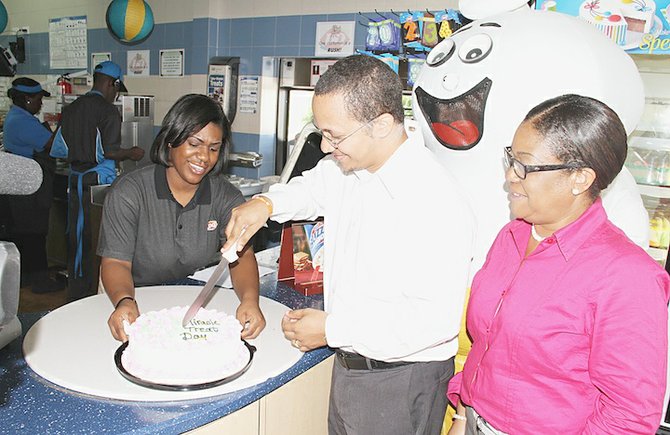 Jason Knowles, the father of Zion Knowles, cuts a miracle treat day cake watched by Dairy Queen operation manager Crystal Campbell, left, and human resources director Deon Dunbar, right. 
