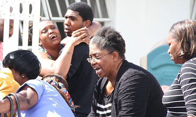 Family and friends in despair at the scene of a house fire yesterday where the body of a young woman was found. Police believe the fire was intentionally started. Photo: Tim Clarke/Tribune Staff