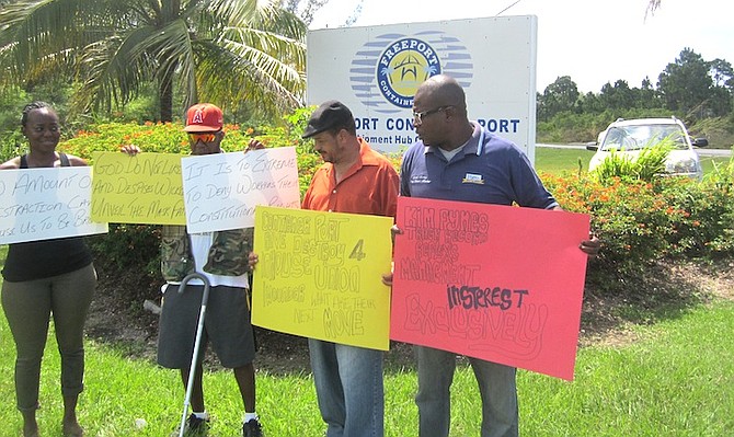 Trade Union activist Lionel Morley (right) and protestors by the Freeport Container Port signage at the traffic circle on Warren Levarity Highway on Friday. Photo: Denise Maycock/The Tribune
