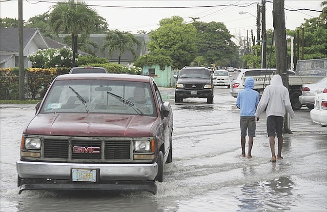 Pedestrians and drivers trying to make their way through floodwaters yesterday after heavy rain hit New Providence. Photo: Tim Clarke/Tribune staff