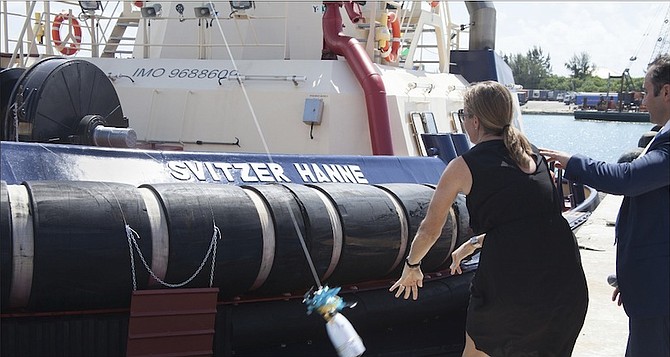 Hanne Helweg, the wife of Martin Helweg, managing director of Svitzer, breaks a ceremonial bottle of champagne on the bow of the refurbished tugboat, Svitzer Hanne. Photo: Dave Mackey

