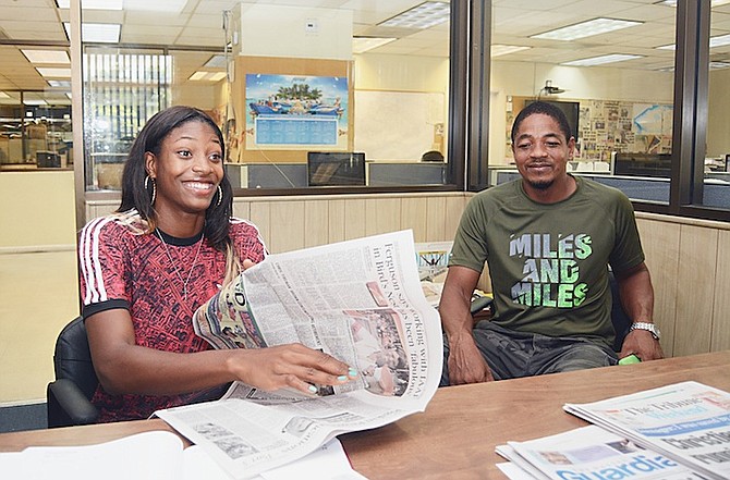 Shaunae Miller looks at The Tribune’s coverage of her performances at the IAAF World Championships in Beijing last month. Miller visited the newspaper’s offices on Friday. Also pictured is her father, Shaun. 
Photo by Shawn Hanna/Tribune Staff 
