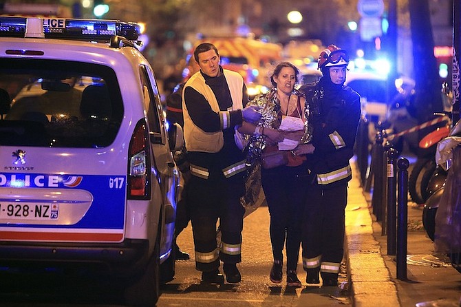 Rescue workers help a woman outside the Bataclan theater in Paris, Friday. (AP)