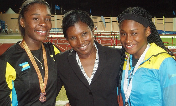 IAAF Councilwoman Pauline Davis shares a moment with Brianne Bethel and Devine Parker after she presented them with their bronze and silver medals respectively from the 100m.