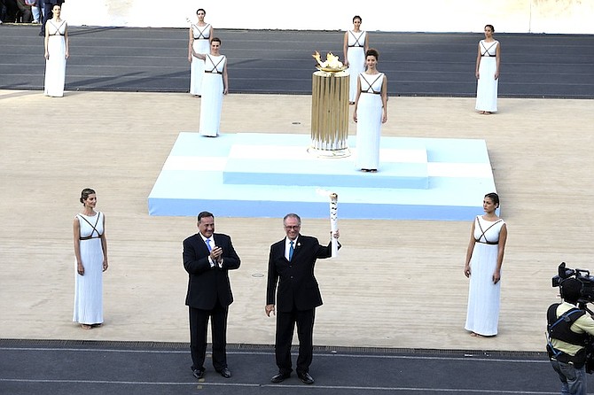 Rio 2016 organising committee president Carlos Nuzman, right, holds a torch with the Olympic Flame as the head of Greece's Olympic Committee, Spyros Capralos applauds during the handover ceremony at Panathinean stadium in Athens, Wednesday. (AP)