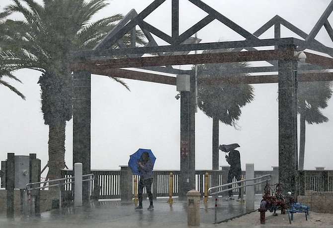 Beach goers get caught in a sudden downpour when a band associated from Tropical Storm Colin came ashore at Clearwater Beach, Monday, June 6, 2016, in Clearwater, Fla. A large portion of Florida's western and Panhandle coast was already under a tropical storm warning when the National Hurricane Center announced that a swift-moving depression had become a named storm. (AP Photo/Chris O'Meara)
