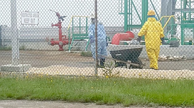 Workers wearing protective clothing are seen cleaning up a chemical spill at the BORCO plant on Friday.
