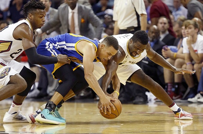 Golden State Warriors guard Stephen Curry, centre, attempts to recover a loose ball against New Orleans Pelicans guard Buddy Hield, left, and forward Solomon Hill right, during the second half of the NBA game in New Orleans, Friday. (AP)