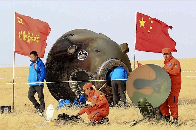 Ground crew check on the re-entry capsule of Shenzhou 11 spacecraft, which brought back a pair of Chinese astronauts from a monthlong stay aboard China’s space station, after it landed in north China’s Inner Mongolia Autonomous Region. China vowed Tuesday to speed up the development of its space industry as it set out its plans to become the first country to soft land a probe on the far side of the moon, around 2018, and launch its first Mars probe by 2020. (Li Gang/Xinhua via AP)
