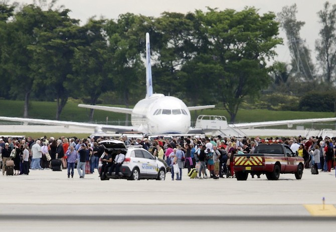 People stand on the tarmac at the Fort Lauderdale-Hollywood International Airport after a shooter opened fire inside a terminal of the airport, killing several people and wounding others before being taken into custody. (AP)