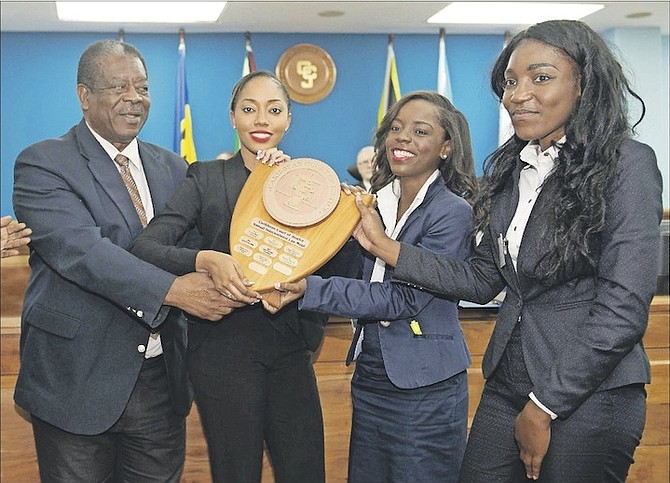 Caribbean Court of Justice President Sir Dennis Byron presents the International Law Moot Court Competition trophy to Raven Rolle, Megan Curry and Janessa Murray, of the Eugene Dupuch Law School, in Trinidad and Tobago.