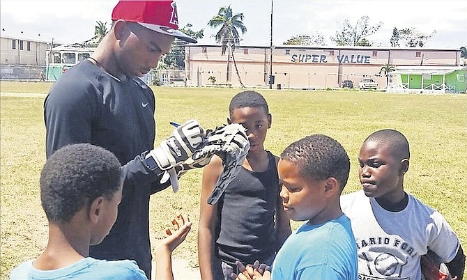 Professional baseball player Trent Deveaux signs a glove for one of the Mario Ford baseball campers at Windsor Field.
