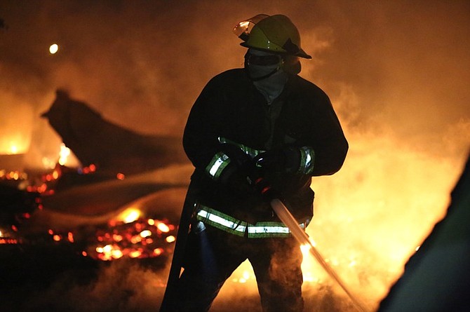 A firefighter tackles the blaze in the shanty town just west of Fire Trail Road.