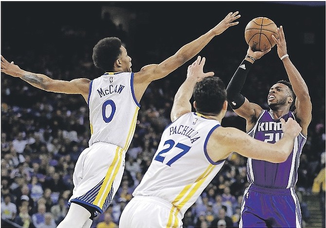 Sacramento Kings’ Buddy Hield, right, shoots against Golden State Warriors’ Patrick McCaw, left, and Zaza Pachulia (27) during the first half of Friday’s game. 
 (AP Photo/Ben Margot)