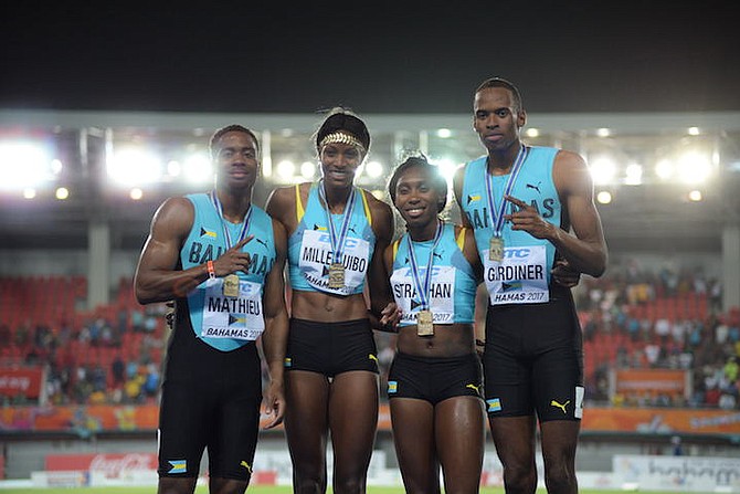 The Bahamas team of Michael Mathieu, Shaunae Miller, Anthonique Strachan and Steven Gardiner celebrate atop the medal podium on Sunday night. Photo: Shawn Hanna/Tribune Staff