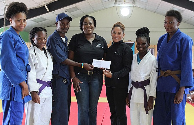 In support of the Bahamas Judo Federation, Consolidated Water (CWCO) representatives Jeff Burrows and Welliya Cargill (centre) present a cheque to 2003 world champion and three-time Olympic medallist Amarilis Savon, who joined the Bahamas Judo Federation as the female coach leading up to last week’s Commonwealth Youth Games. Shown (l-r) in traditional judo uniform or ‘judogi’ are Breanna Major, Commonwealth Youth Games bronze medallist Mya Beneby, Jasmine Russell and Davante Sweeting.
