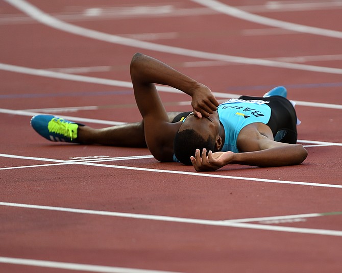 RECORD HOLDER: Steven Gardiner lies on the track after his victorious semifinal run. Photo: Kermit Taylor/Bahamas Athletics