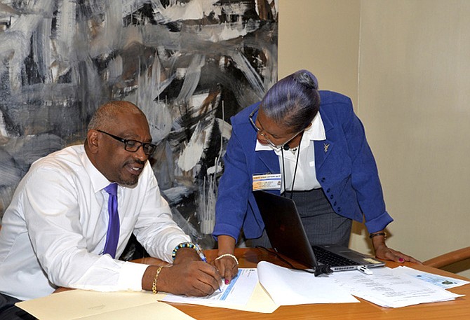 Prime Minister Dr Hubert Minnis taking part in the verification process for all public service employees, assisted by Donna Delancy, deputy treasurer and co-ordinator of the verification process. 