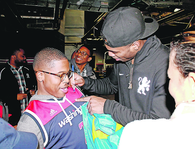 Bahamian NBA star Buddy Hield autographs the jersey of a Wizards fan.