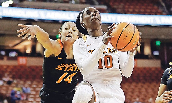 Texas guard Lashann Higgs (10) drives to the basket past Oklahoma State guard Braxtin Miller (14) during the first half of Wednesday’s NCAA college game in Austin, Texas.
