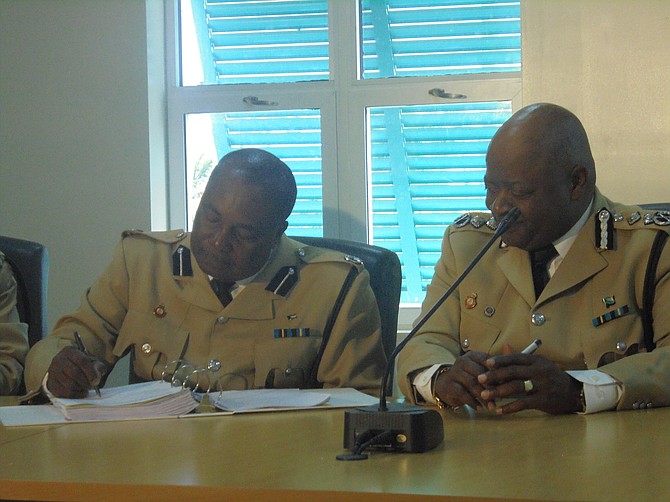 Deputy Commissioner of Police Emrick Seymour turns over command of the Grand Bahama District to Assistant Commissioner of Police Samuel Butler at the handover signing ceremony at Police Headquarters in Grand Bahama on Friday. Photos by Denise Maycock. 