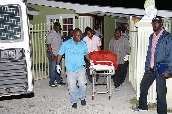 Police remove the body of one of the victims from Saffron Street, Pinewood Gardens, on Friday night.