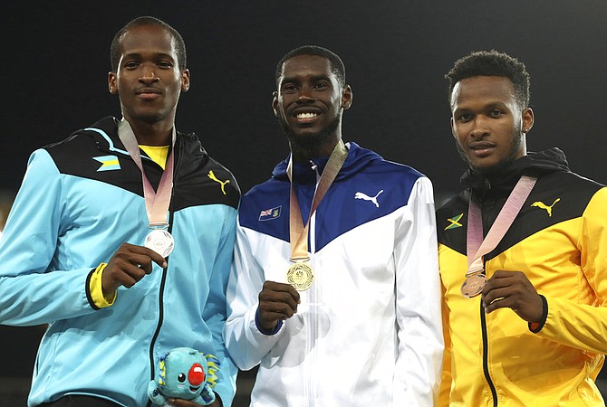 Men's 400m hurdles gold medalist Kyron McMaster of the British Virgin Islands stands with silver medalist Jeffery Gibson, left and bronze medalist Jamaica's Jaheel Hyde on the podium at Carrara Stadium during the 2018 Commonwealth Games on the Gold Coast, Australia, Thursday. (AP Photo/Mark Schiefelbein)