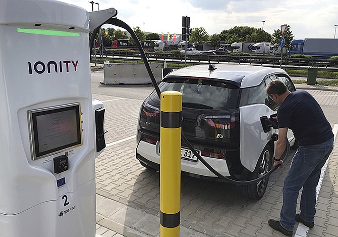 A man charges his BMW electric vehicle at the rest stop Brohltal Ost at the A61 motorway in Niederzissen, Germany. Munich-based Ionity build a highway network of fast charging stations that will let drivers plug in, charge in minutes instead of hours, and speed off on their way, from Norway to southern Italy and Portugal to Poland. Photo: Ferdinand Ostrop/AP

 