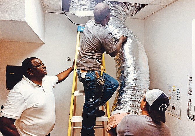 PHA chief engineer Terrance Cartwright, left, supervises as the air conditioning is restored at Eight Mile Rock Community Clinic.