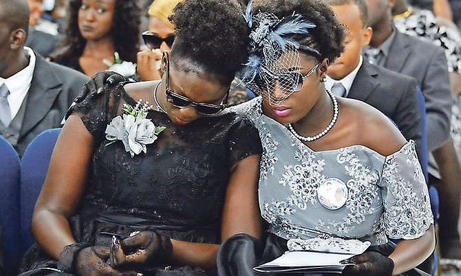 Cassandra, left, and Carleisa Blatch at the funeral service yesterday for their father, Inspector Carlis Blatch, at the Church of God Auditorium. Carleisa is wearing a badge saying “Love you my daddy my hero”. Photo: Shawn Hanna/Tribune Staff