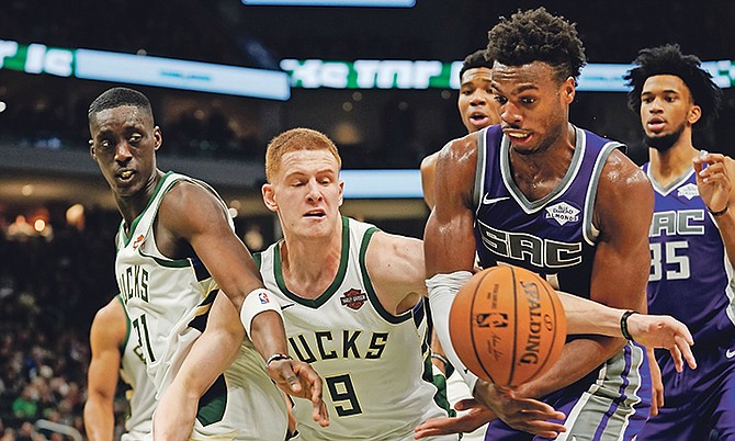 Milwaukee Bucks’ Tony Snell (21) and Donte DiVincenzo (9) battle for a loose ball with Sacramento Kings’ Buddy Hield during the first half on Sunday. (AP Photo/Morry Gash)