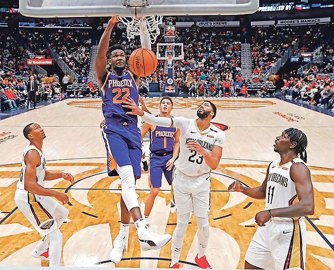 Phoenix Suns center Deandre Ayton (22) slam dunks over New Orleans Pelicans forward Wesley Johnson, left, forward Anthony Davis (23) and guard Jrue Holiday (11) in the second half of an NBA basketball game in New Orleans, Saturday, Nov. 10, 2018. The Pelicans won 119-99. (AP Photo/Gerald Herbert)
