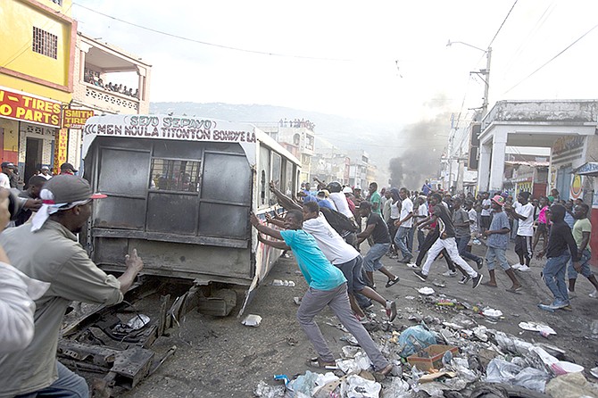 DEMONSTRATORS push a broken bus to burn at a barricade during an opposition protest in Port-au-Prince, Haiti, Sunday.
(AP Photo/Dieu Nalio Chery)