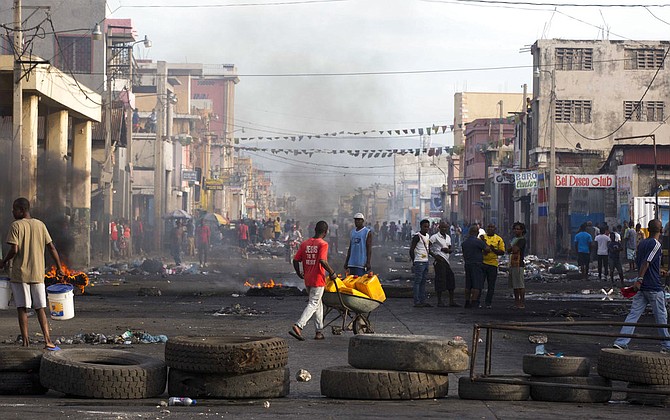 Residents walk amid road blocks placed by anti-government protesters along Boulevard Jean-Jacques Dessalines, a main commercial artery, during a strike against alleged government corruption in Port-au-Prince, Haiti, Wednesday. (AP)