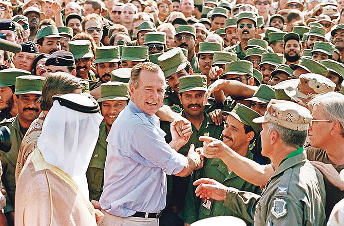 President George H.W. Bush is greeted by Saudi troops and others as he arrives in Dhahran, Saudi Arabia, for a Thanksgiving visit in November, 1990. (AP Photo/J. Scott Applewhite, File)