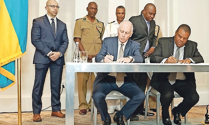 Left, Gary Bunyard, senior vice president, and Eugene Poitier, acting permanent secretary of national security, sign the contracts.