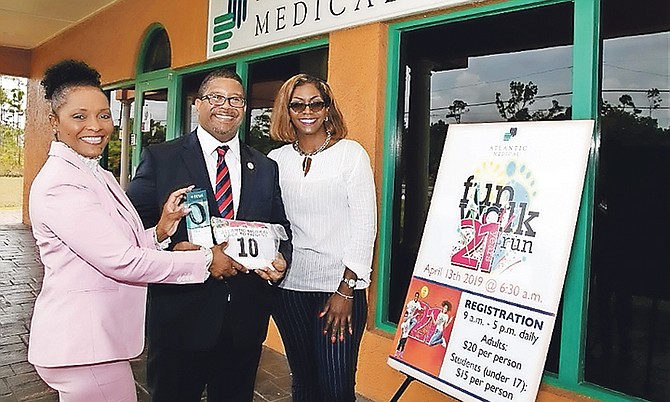 Deputy Prime Minister K Peter Turnquest receives his race kit from Shandra Moss-Styles (left), retention manager with Atlantic Medical Freeport, and Lisa Turnquest, office manager in Freeport.